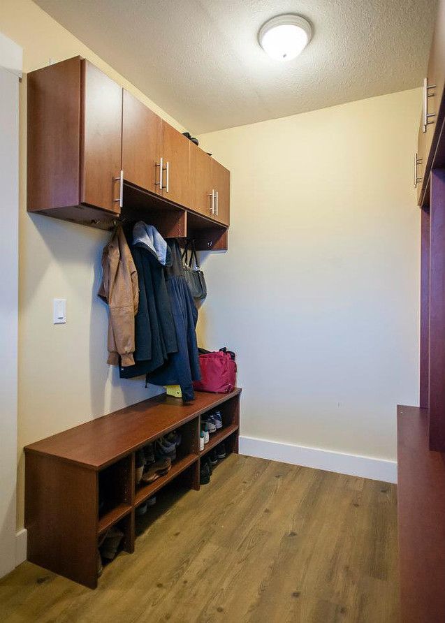 Small entryway with wood bench, coat hooks, cubbies, and a hardwood floor under ceiling light.