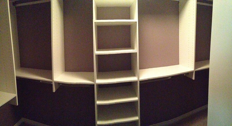 Open closet or pantry with shelves and a ladder centered against a dark wall.
