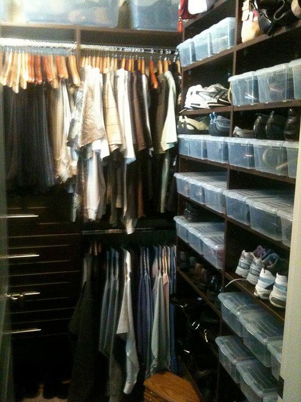 Closet with hanging clothes, folded items, and rows of clear shoe boxes on shelves