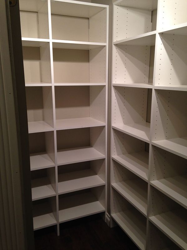 Empty white walk-in closet with built-in shelves and hanging rods, viewed from the doorway.