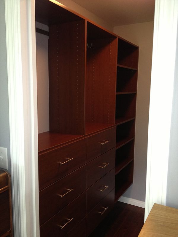 Walk-in closet with dark wood shelving, drawers, and hanging space in a doorway alcove