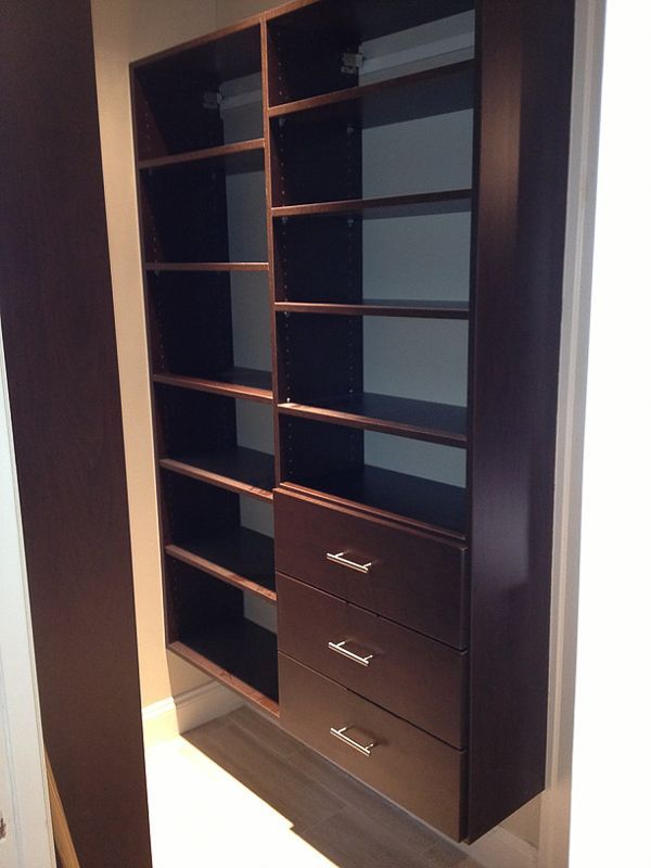 Open dark wood closet with shelves and drawers in a doorway