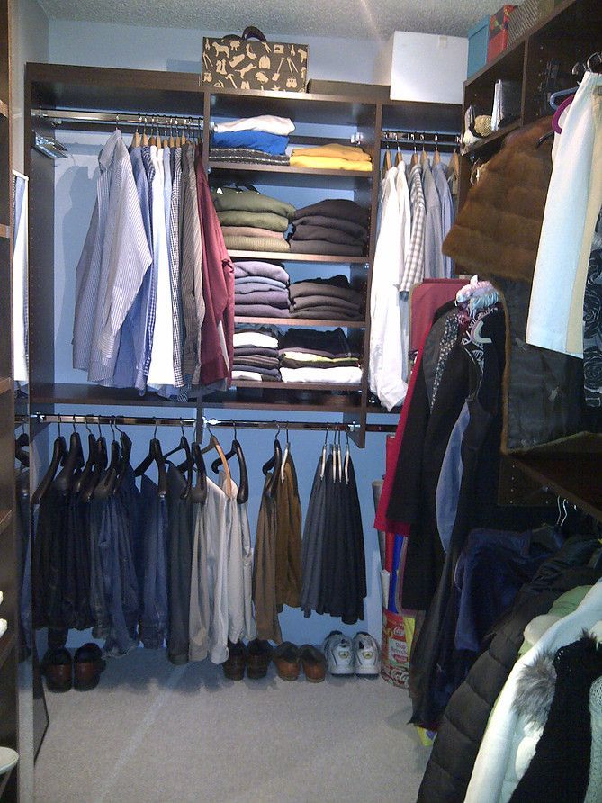 Open closet with shirts, jackets, and folded clothes on shelves and hanging rods.