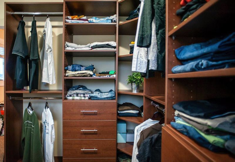 Open closet with shelves, drawers, and hanging clothes folded neatly on both sides.