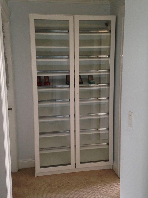 Tall white display cabinet with glass doors in a beige room
