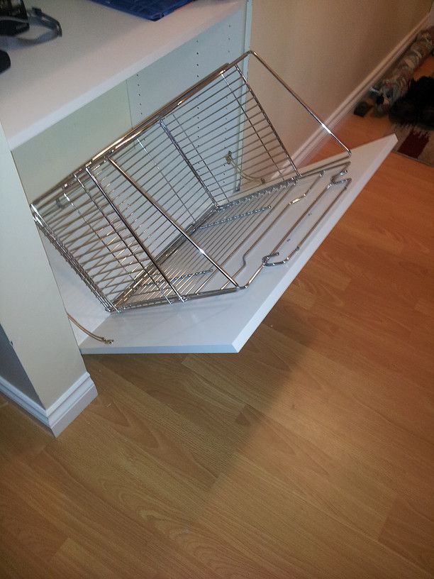 Chrome wire dish rack on a white kitchen counter above a wood floor