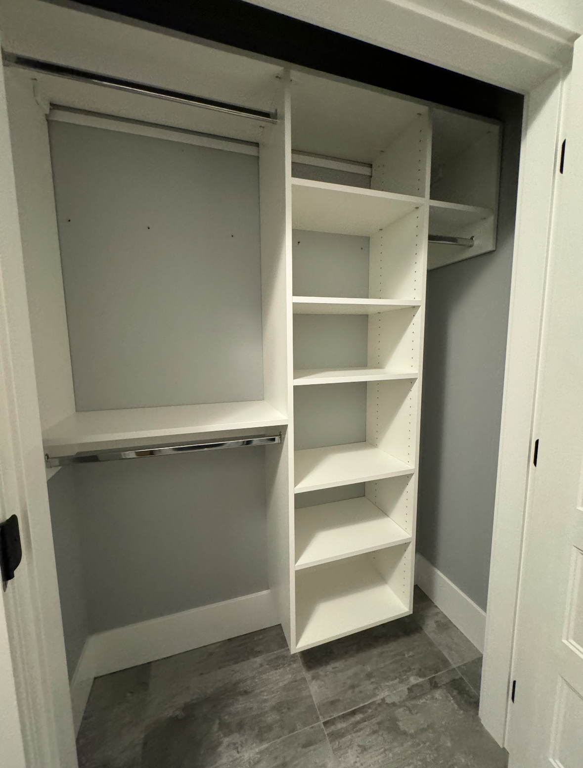 Built-in closet with white shelves, hanging rod, and gray tile floor.