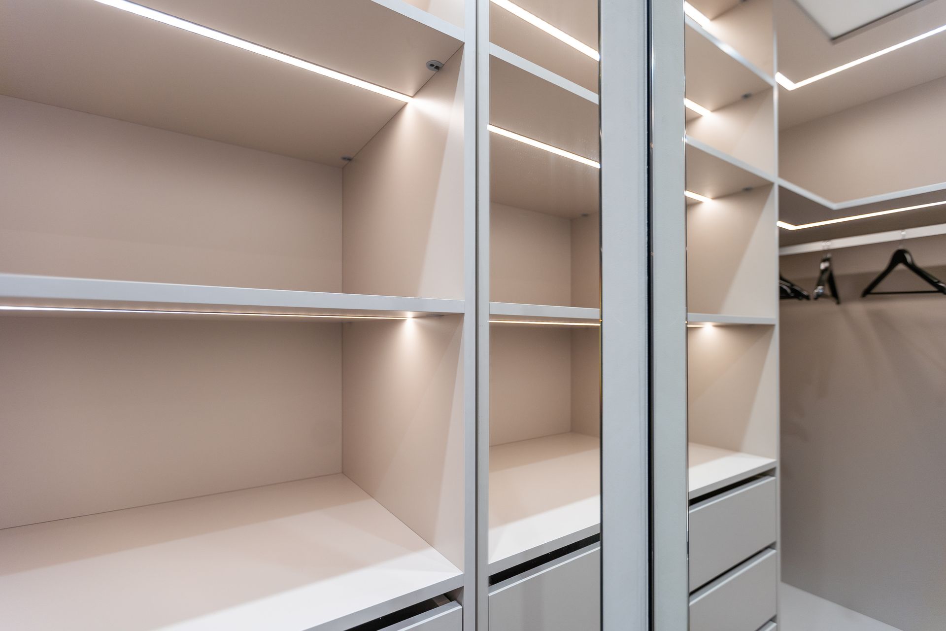 Walk-in closet with dark shelving, drawers, and hanging space, viewed from the doorway.