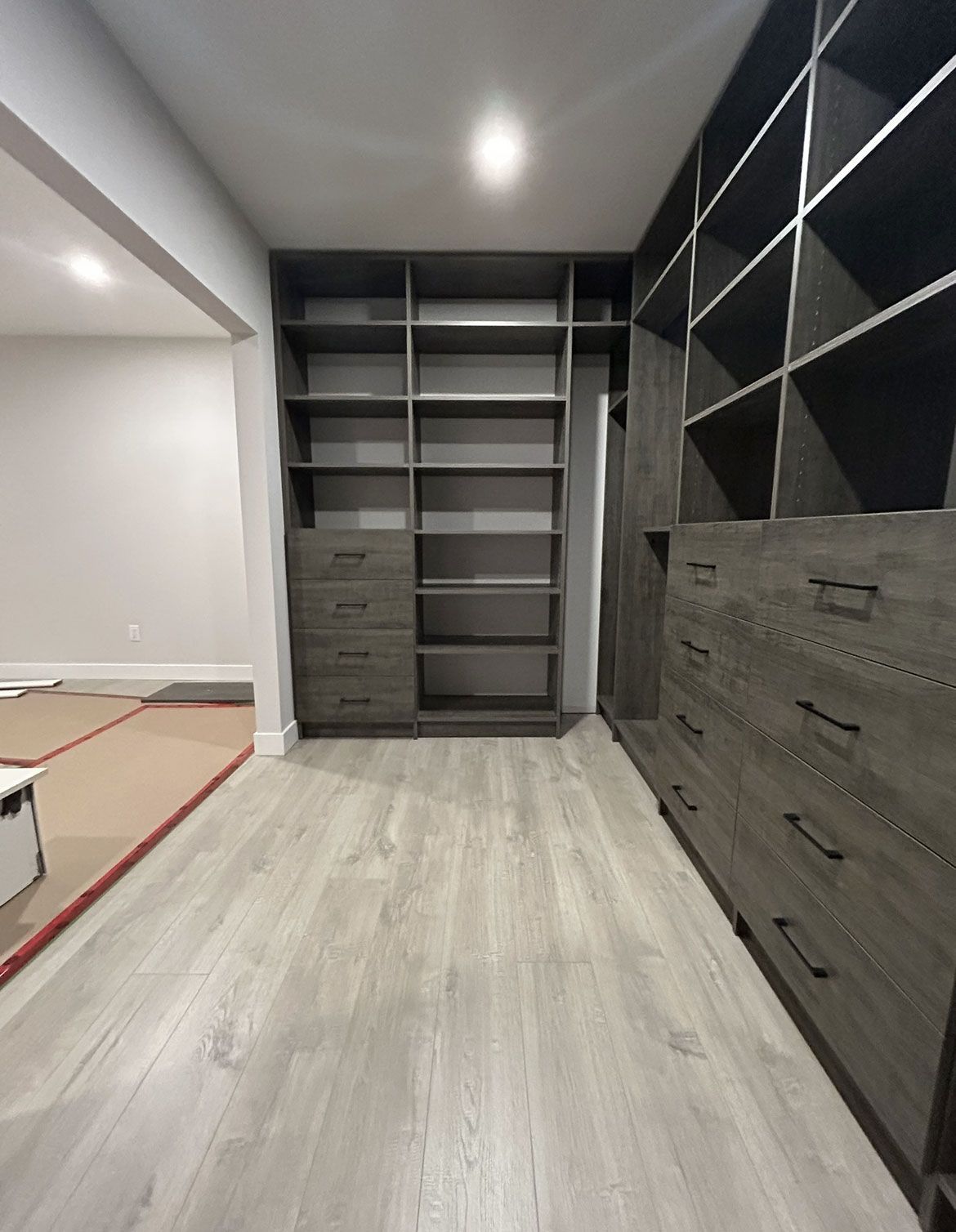 Modern built-in closet with gray shelves, drawers, and cubbies in a home hallway.