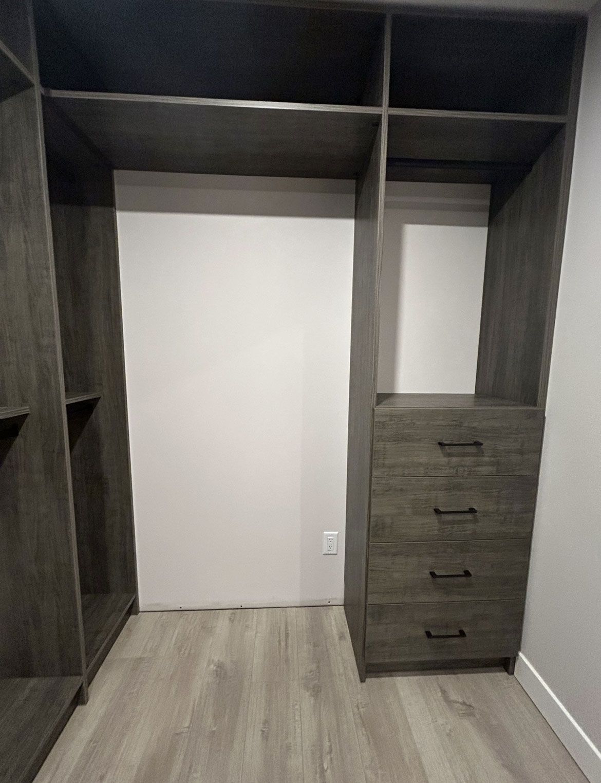 Empty walk-in closet with dark wood shelving, hanging space, and a drawer unit on the right.