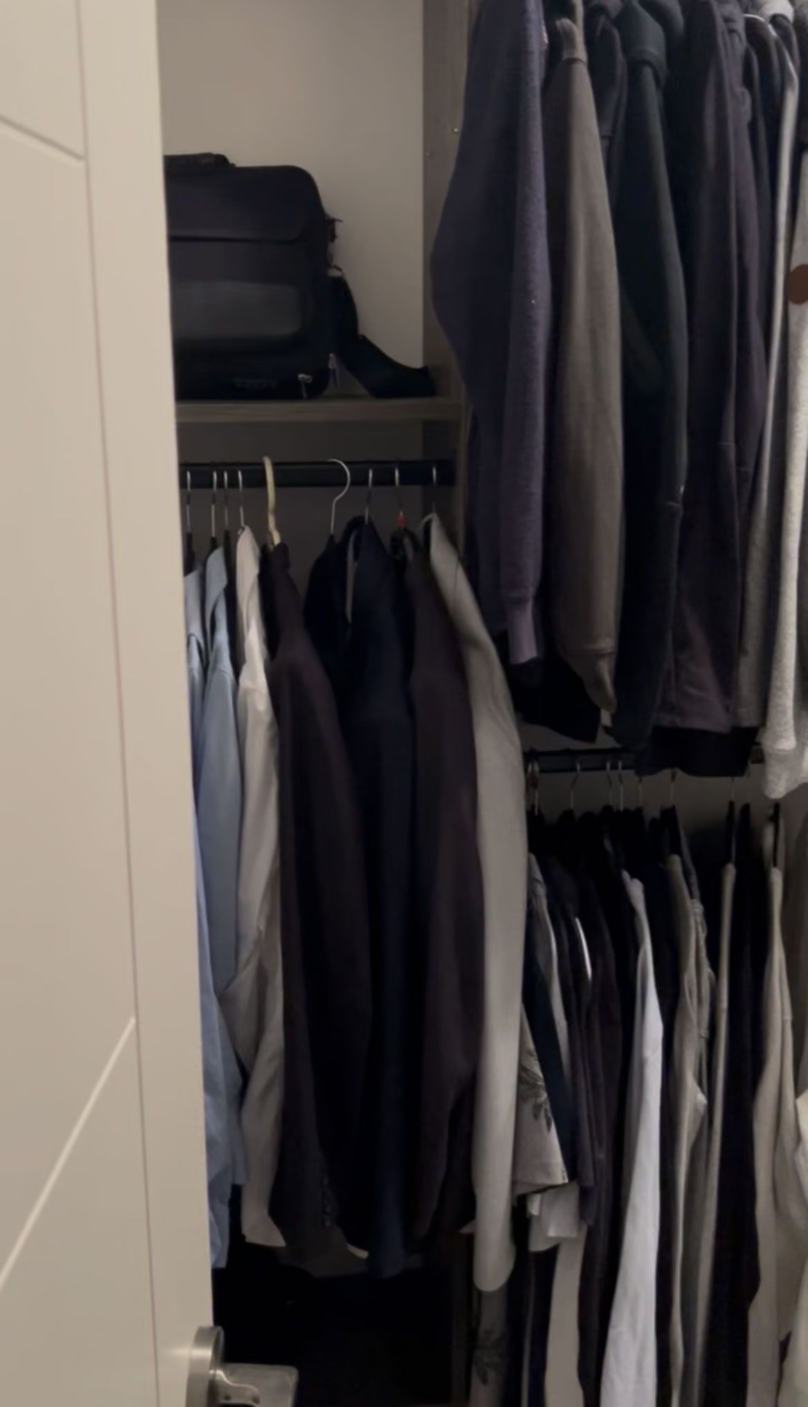 Open closet with hanging clothes, shelves, and shoes in a narrow storage space