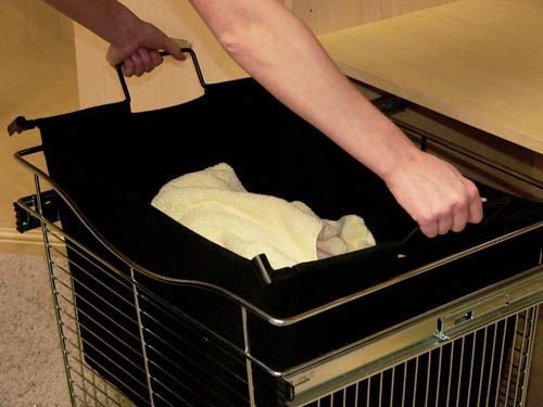 Hands lowering a folded white cloth into a black laundry cart on wheels