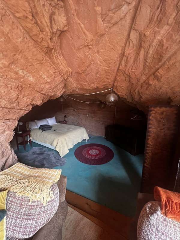 A cave bedroom with a queen bed and sculpted sandstone ceiling