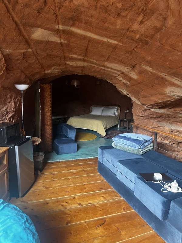 A cave room with a queen bed and a blue couch
