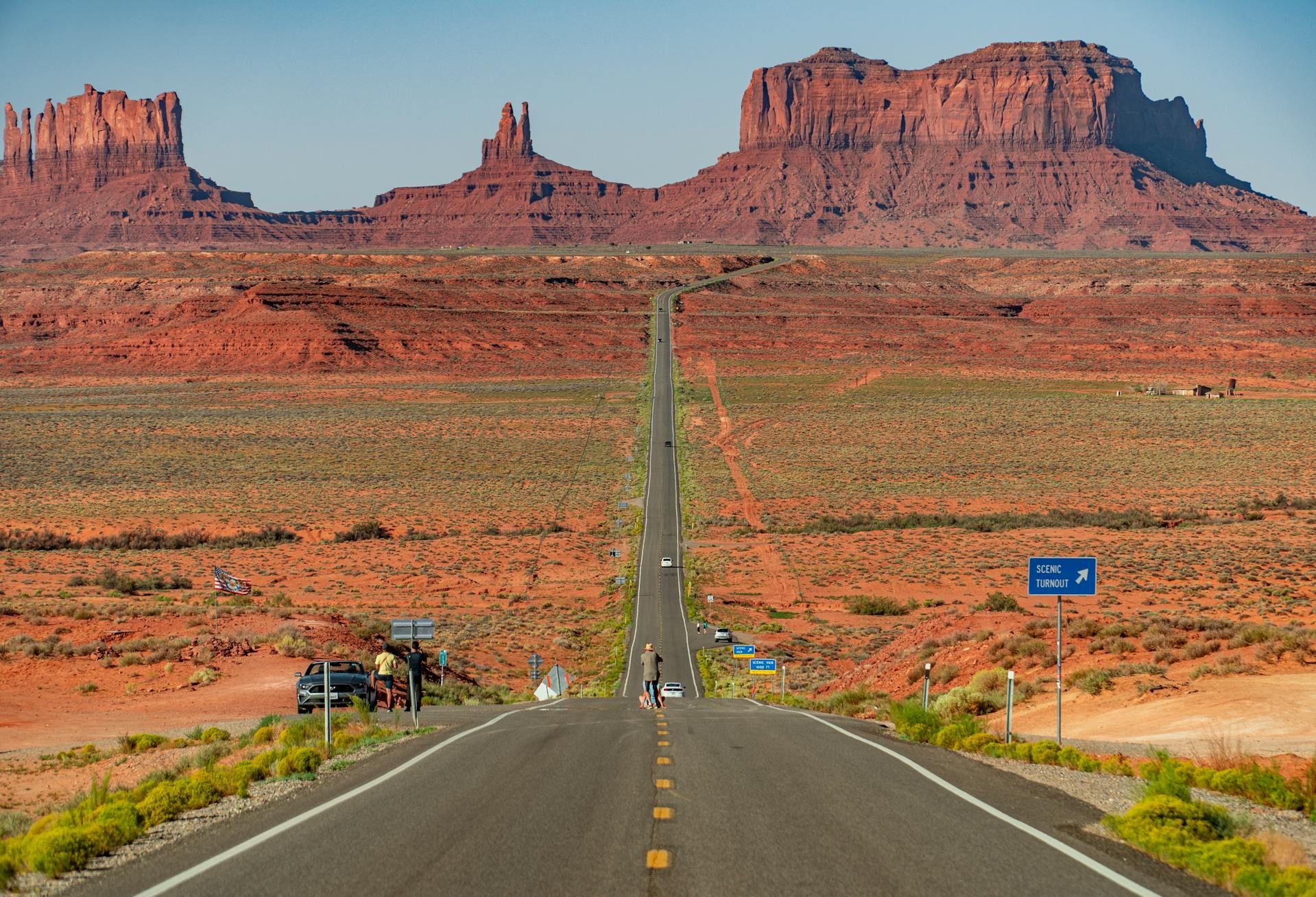 Paved road through desert landscape towards iconic red rock formations in Monument Valley.