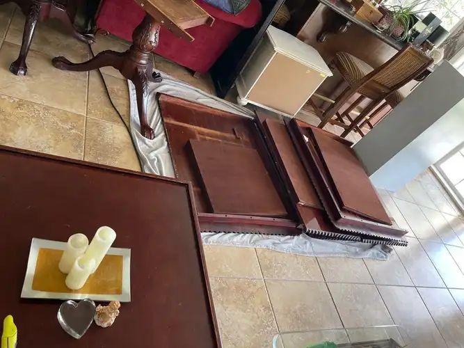 Wooden furniture disassembled on floor covered with drop cloth. Candles on a table.