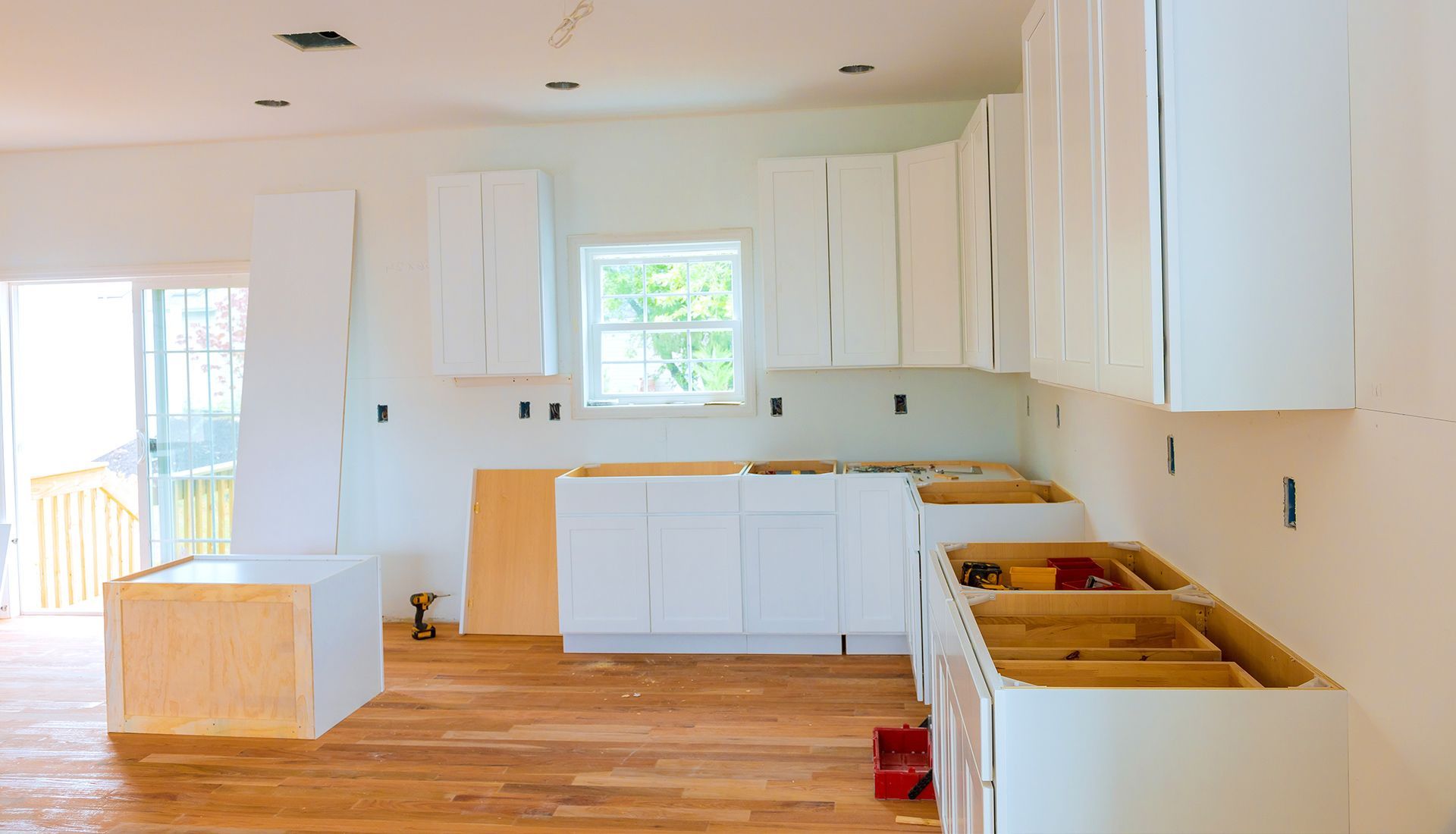 Modern kitchen with white countertops and cabinets, wooden island, stainless steel appliances, and a hanging light.