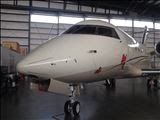 White business jet in a hangar, nose-on view.