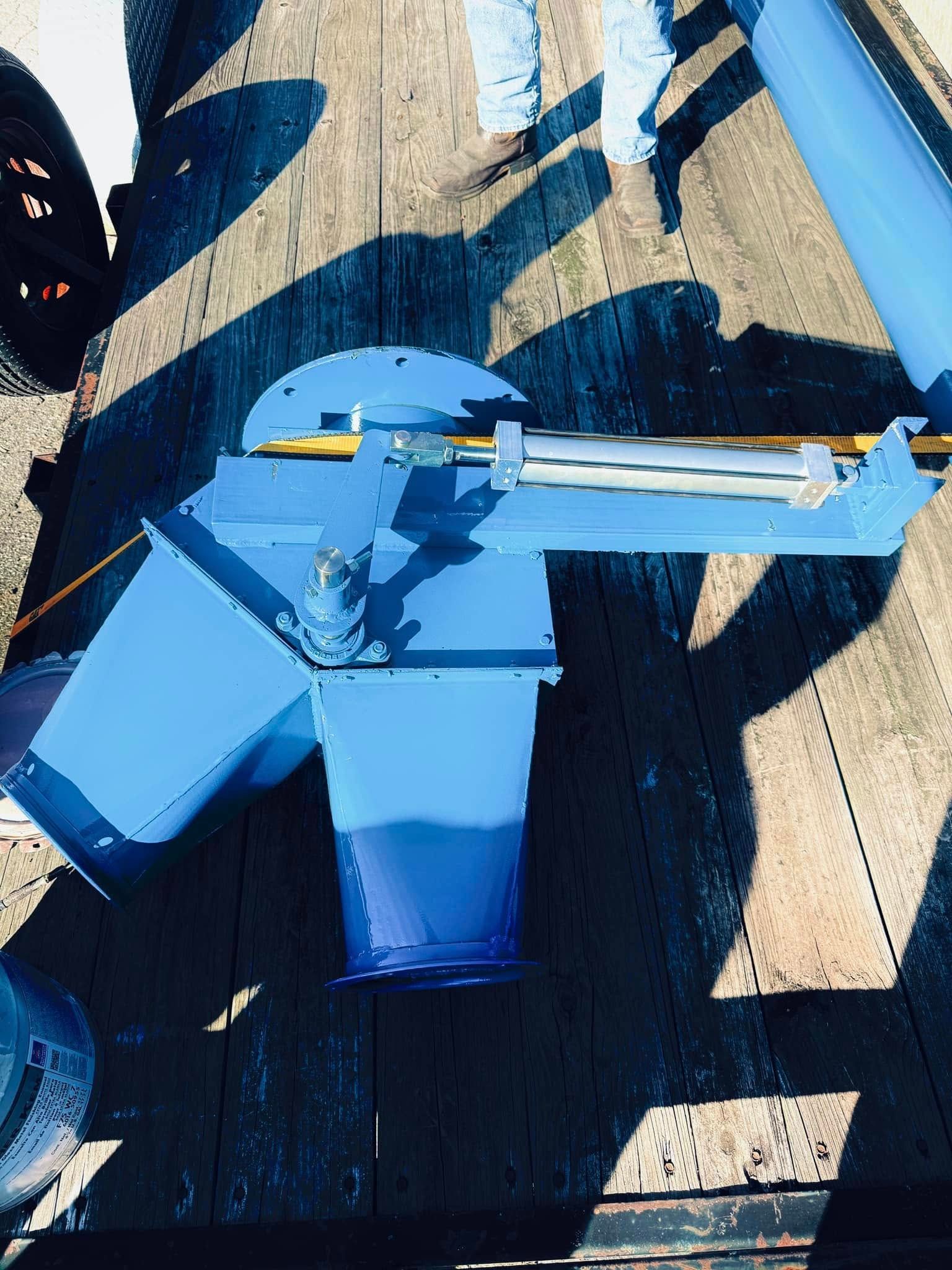 Blue painted machinery on a wooden surface, with shadows.