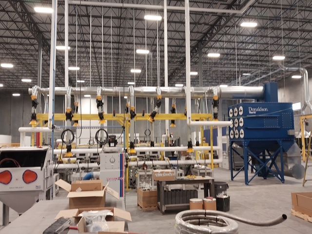 Industrial facility with machinery and piping; blue dust collector.