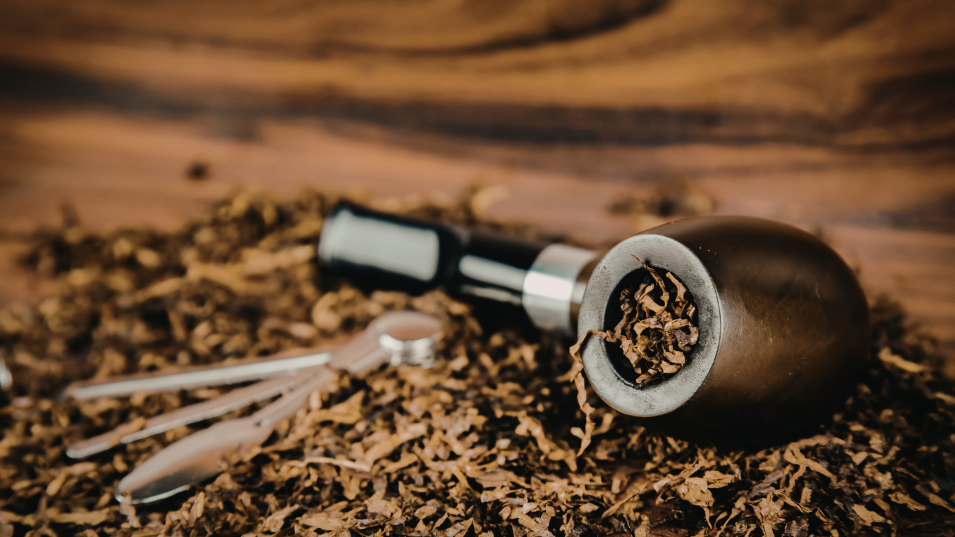 Close-up of a wooden tobacco pipe and spilled loose tobacco on a rustic wooden surface