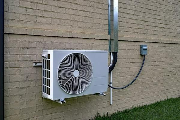 A White Air Conditioner Is Mounted On The Side Of A Brick Building — Jervis Bay Airconditioning In Kiama, NSW