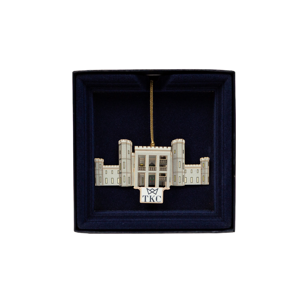Ornament of a white building in a dark blue box with a gold hanging string.