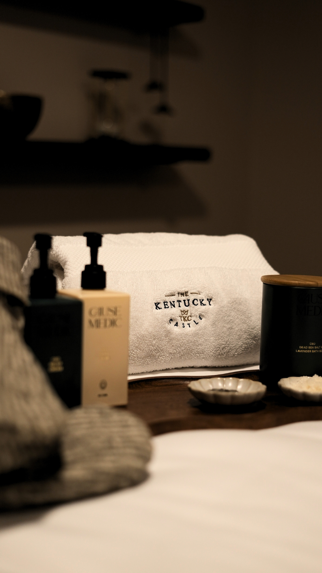 Spa setting with white towel, toiletries, and a lit candle.