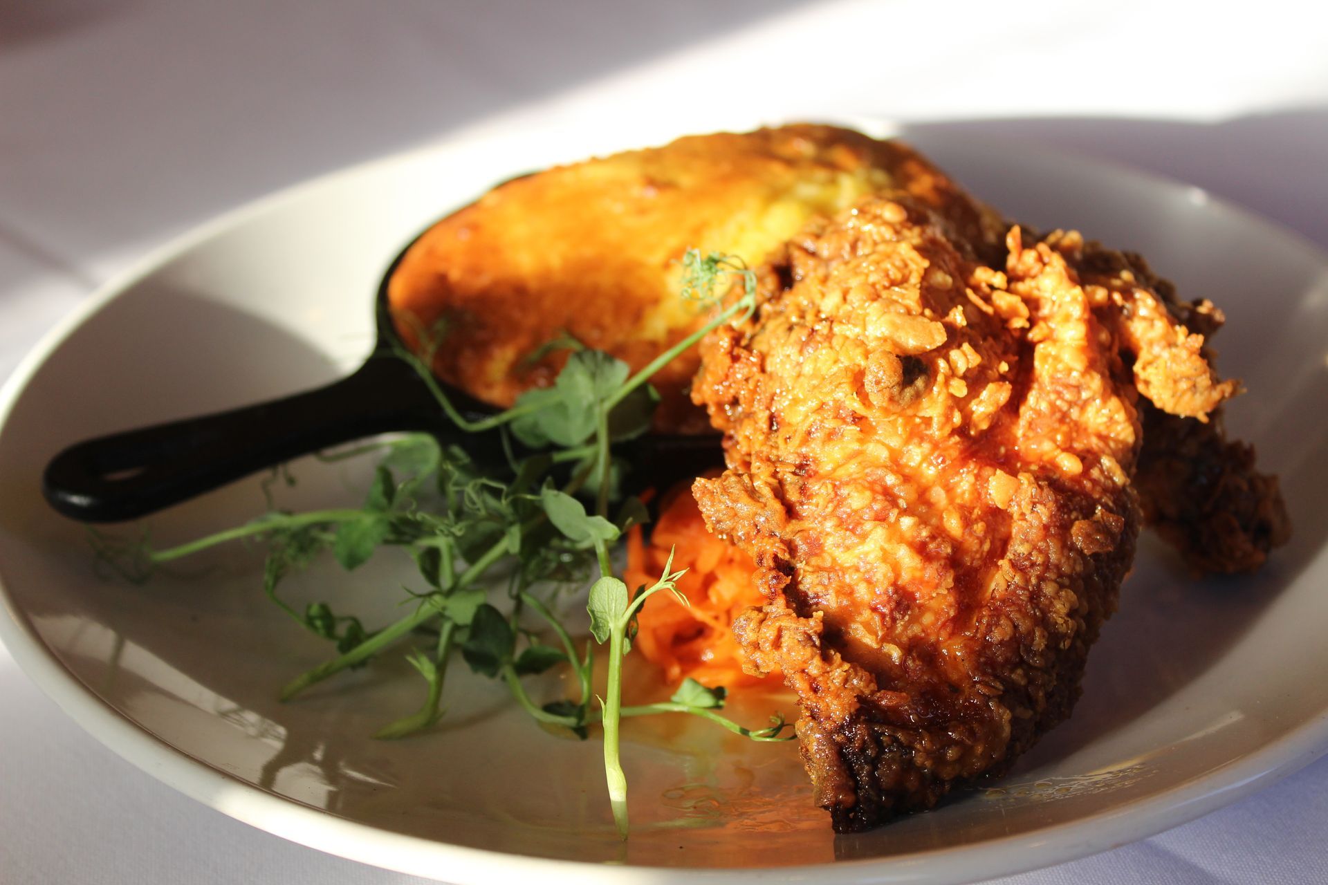 Fried chicken and side dish on a white plate, with green garnish.