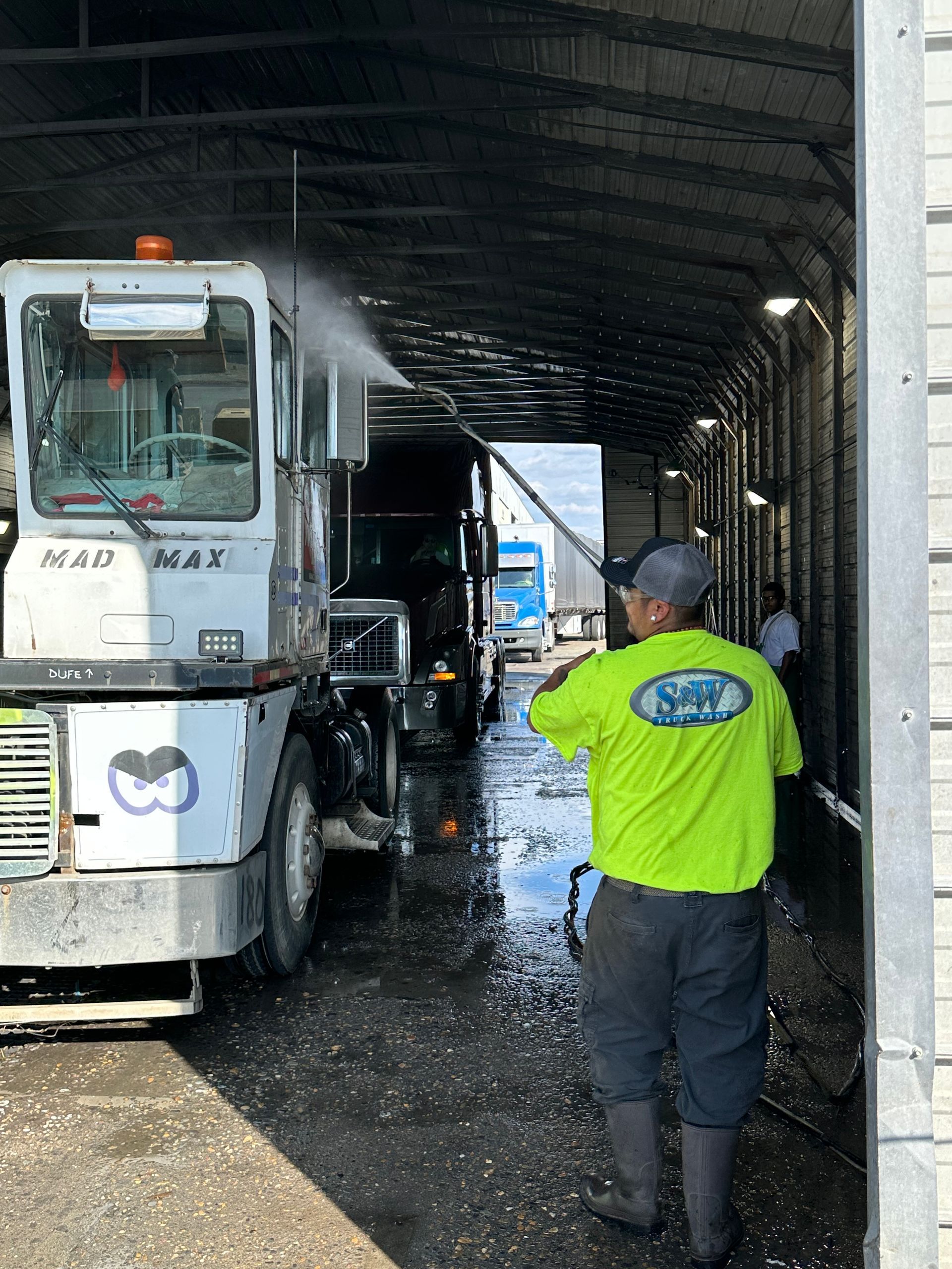 Person power washing the red front of a large truck.