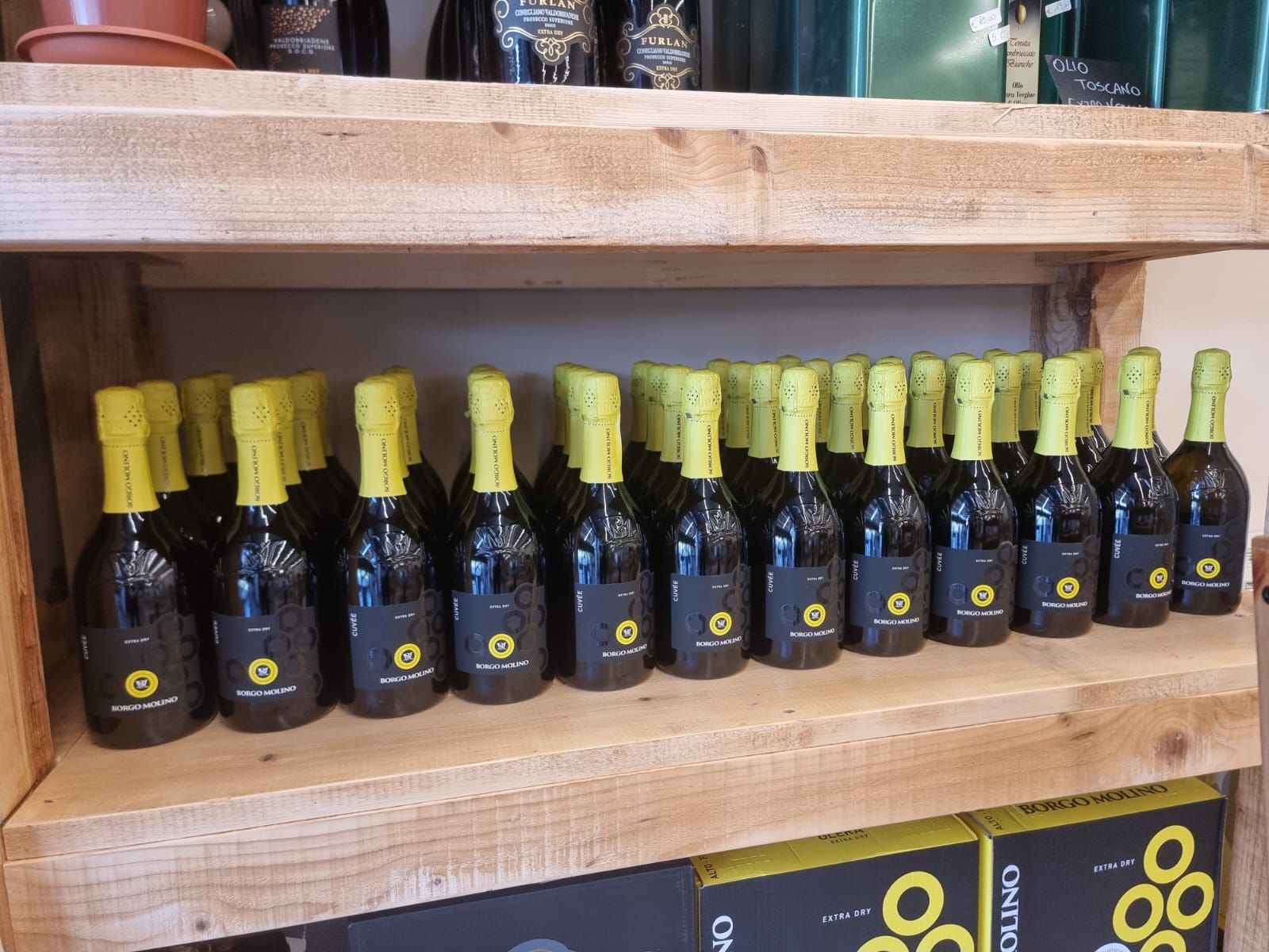 Scaffali di legno su cui sono esposte numerose bottiglie scure con tappi gialli.