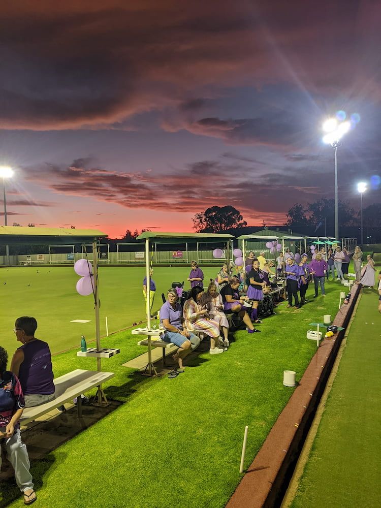 A Group Of People Are Sitting On Benches On A Field At Night — Inverell Sporties in Inverell, NSW