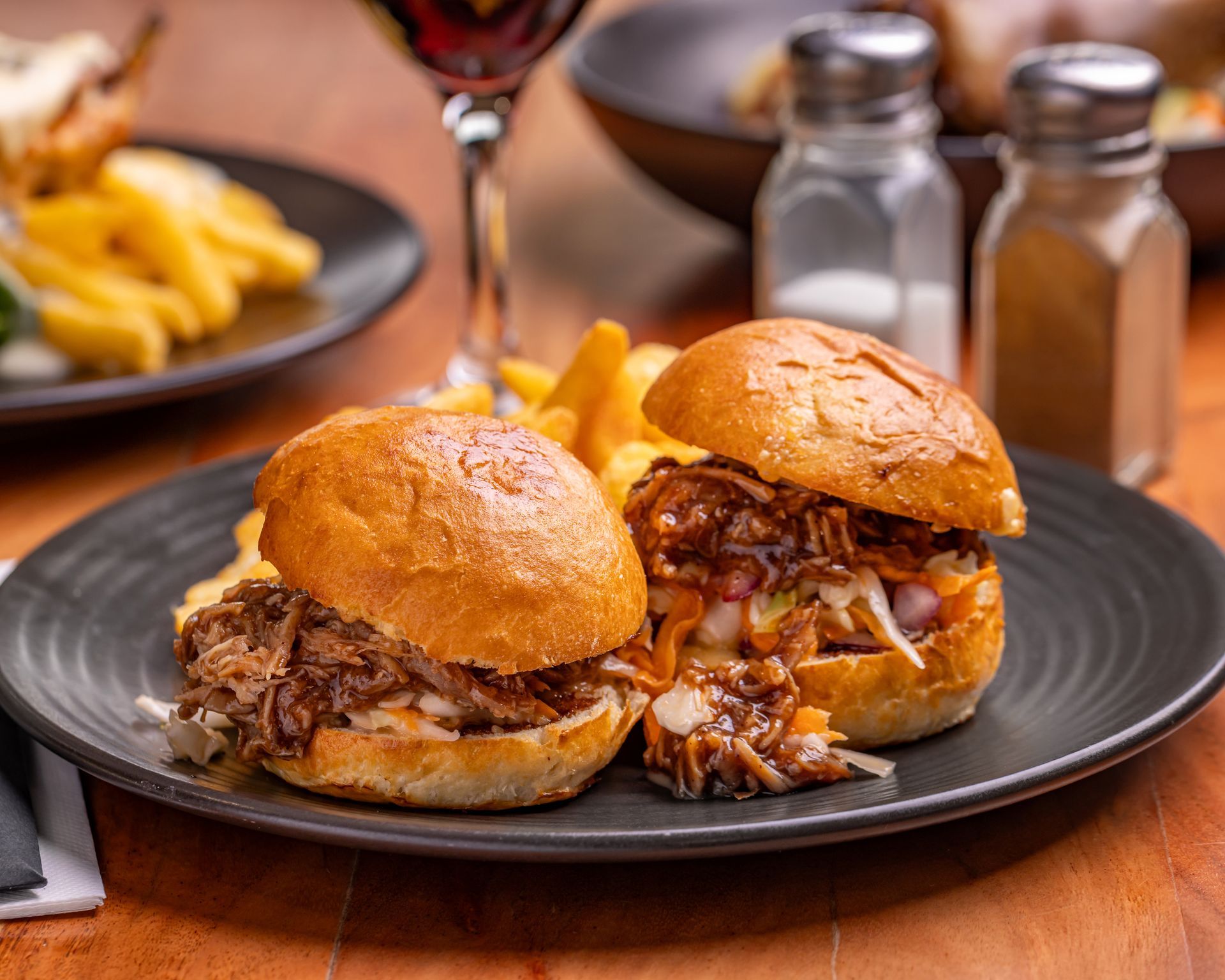 Pulled Pork Sliders on a Plate With Fries, Salt, Pepper, and Wine in a Restaurant Setting — Inverell Sporties in Inverell, NSW