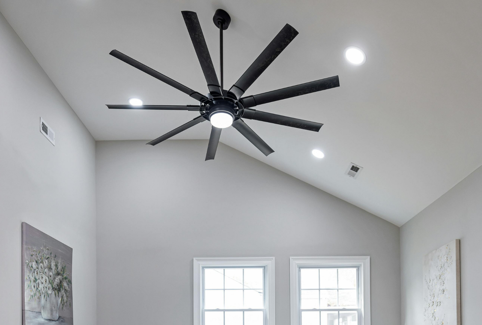 Vaulted white room with a large black ceiling fan and two windows.