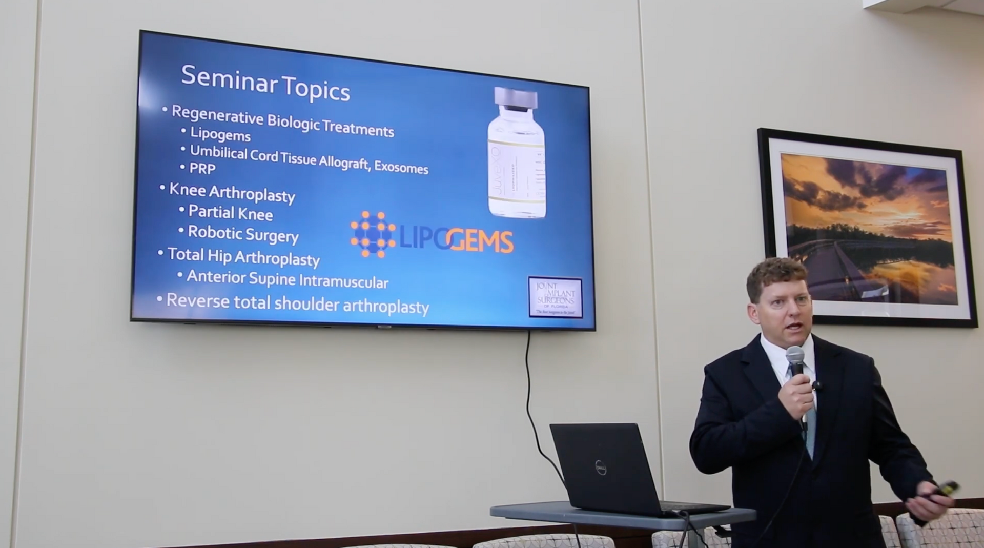 Man presenting seminar topics, using a laptop, with a screen displaying a vial and a list.
