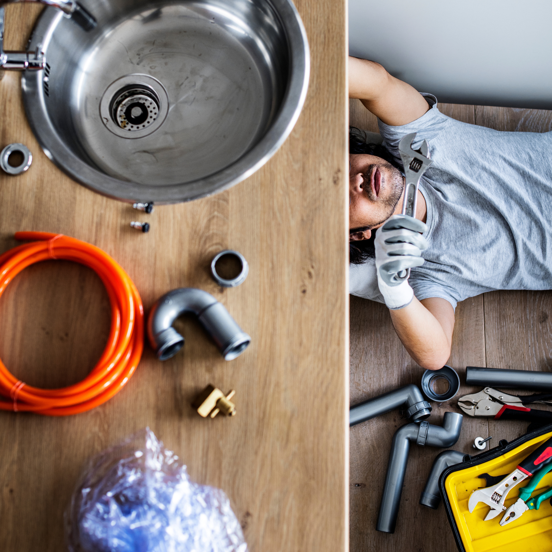 A man is laying on the floor next to a sink.
