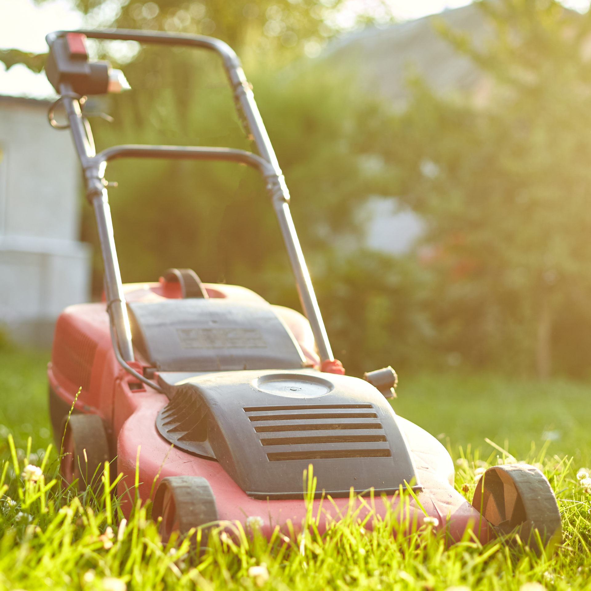 A red lawn mower is sitting in the grass.