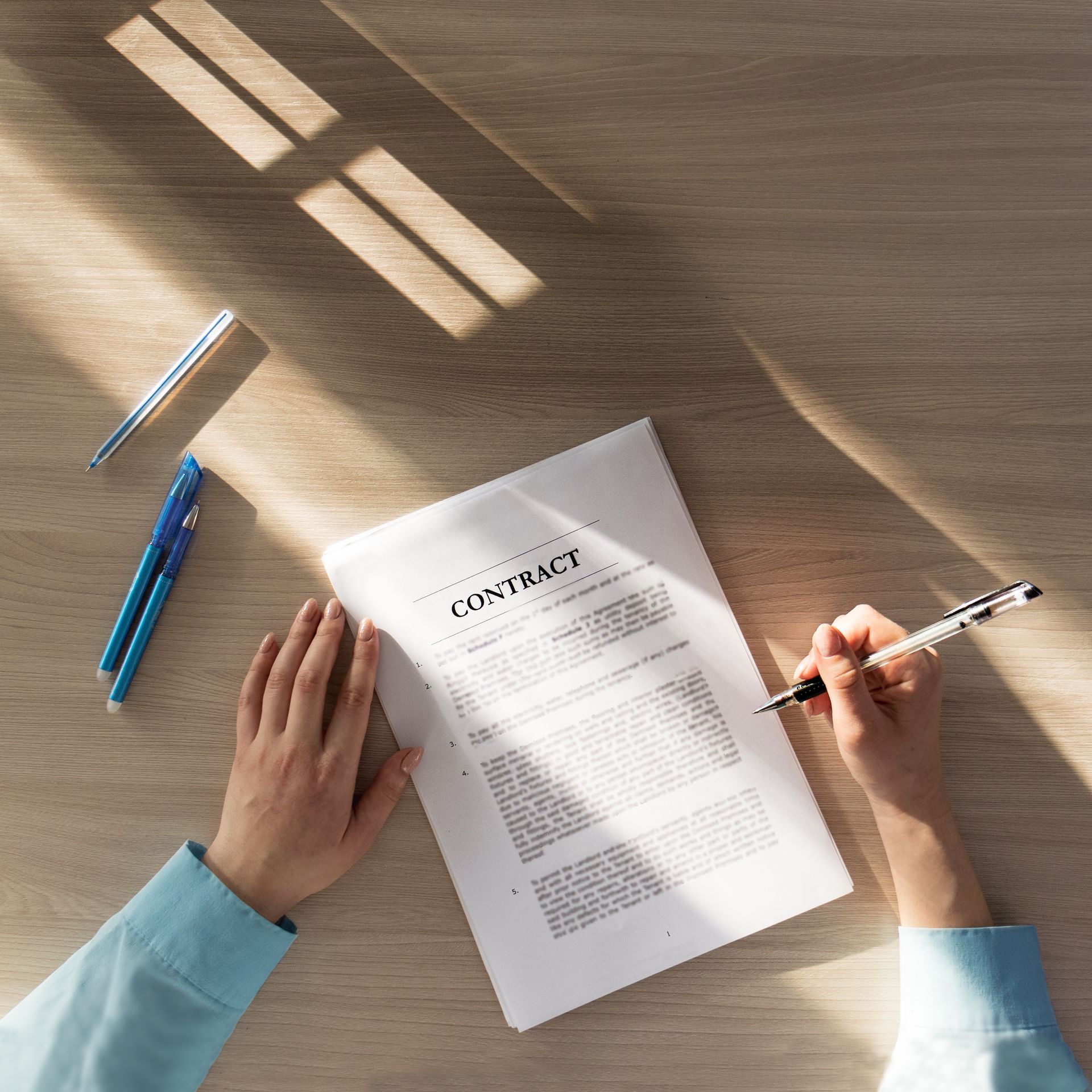 A person is writing on a piece of paper that says contract