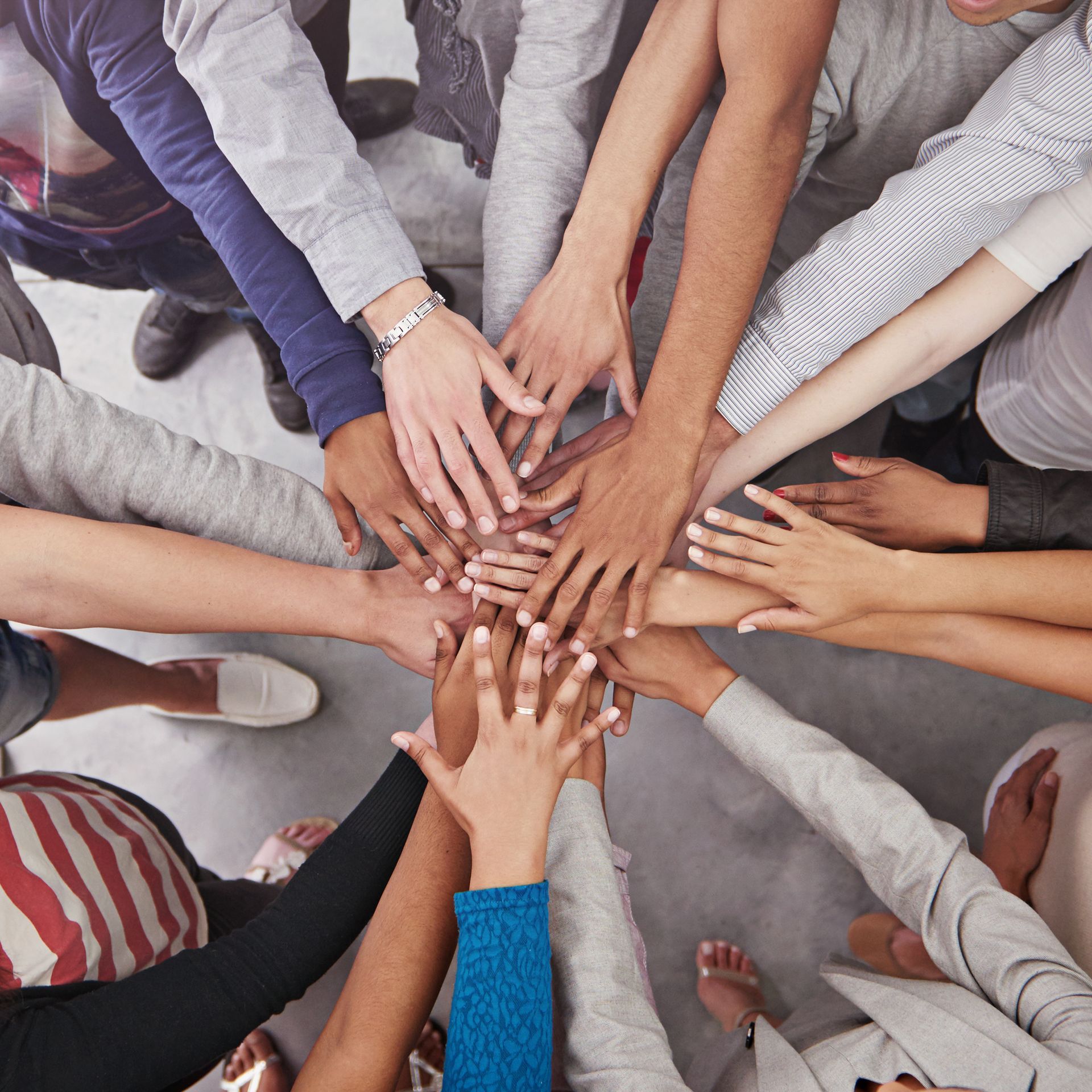 A group of people are putting their hands together in a circle