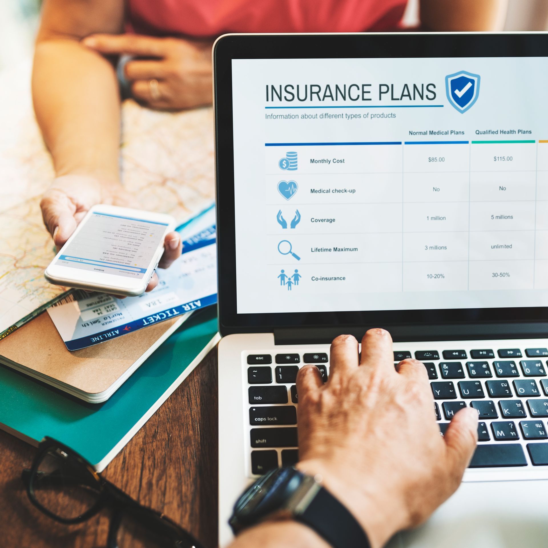 A person is typing on a laptop with an insurance plan on the screen