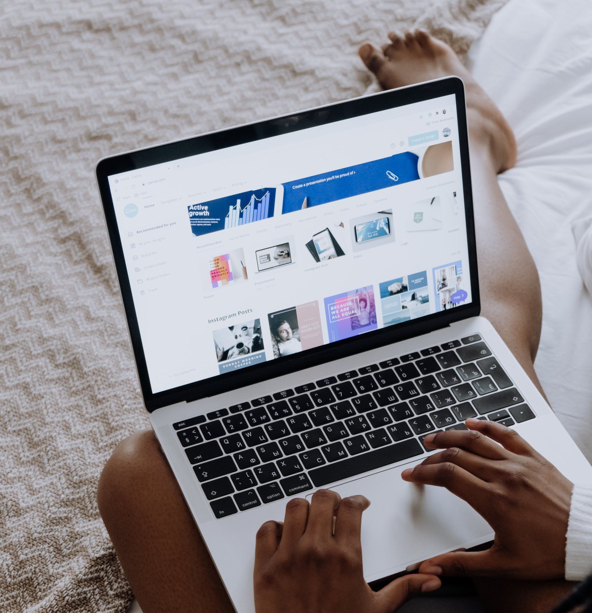 A person is sitting on a bed using a laptop computer.