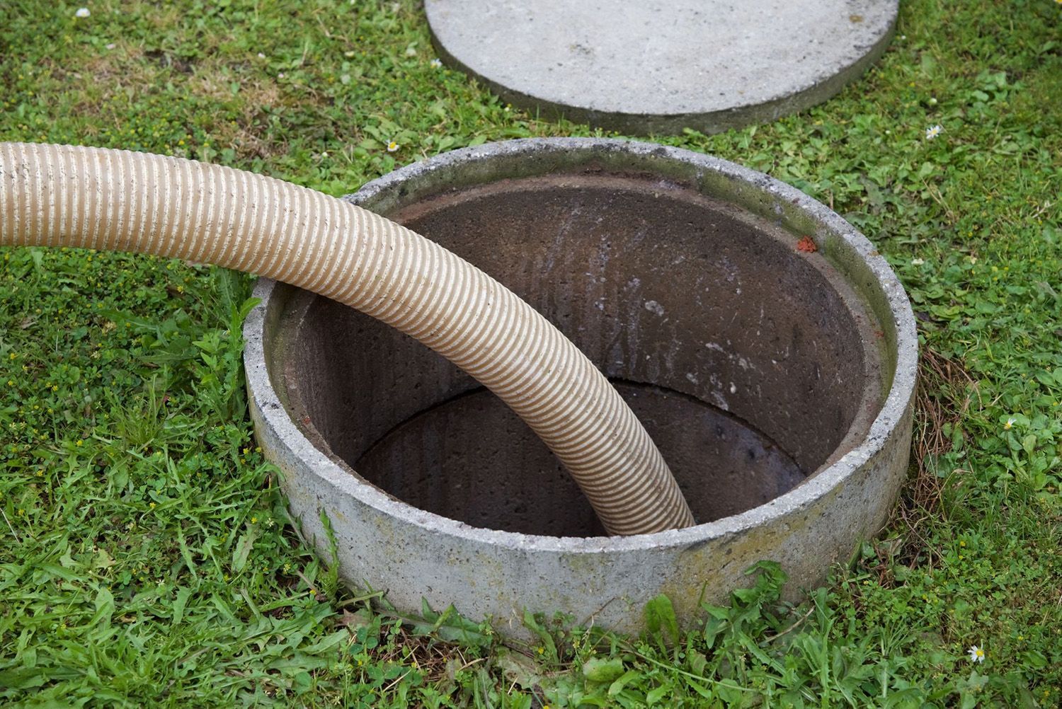 A Vacuum Hose Pumping Out A Residential Concrete Septic Tank