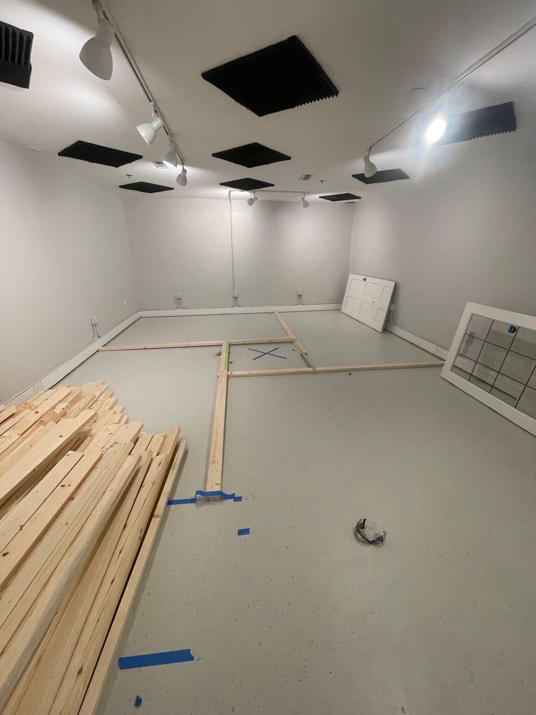 Empty room under construction with wood planks, gray floor, white walls and ceiling, and black vents. Empty room under construction with wood planks, gray floor, white walls and ceiling, and black vents.