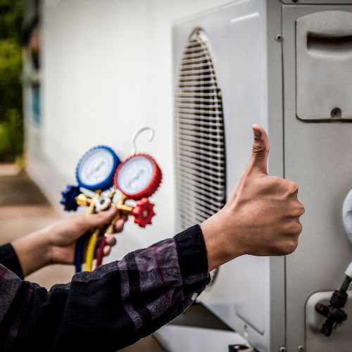 A person is giving a thumbs up in front of an air conditioner
