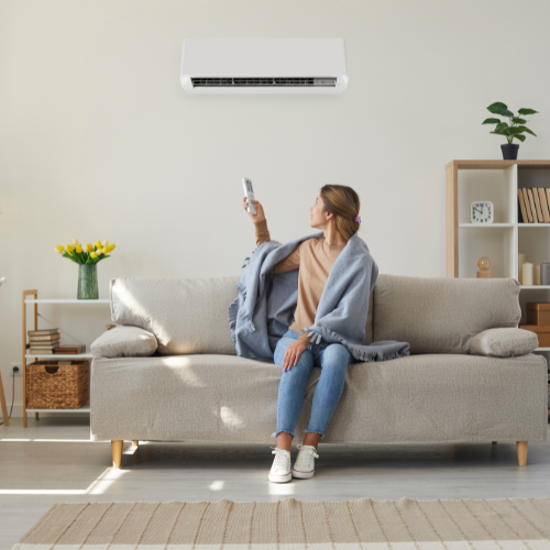 A woman is sitting on a couch holding a remote control.