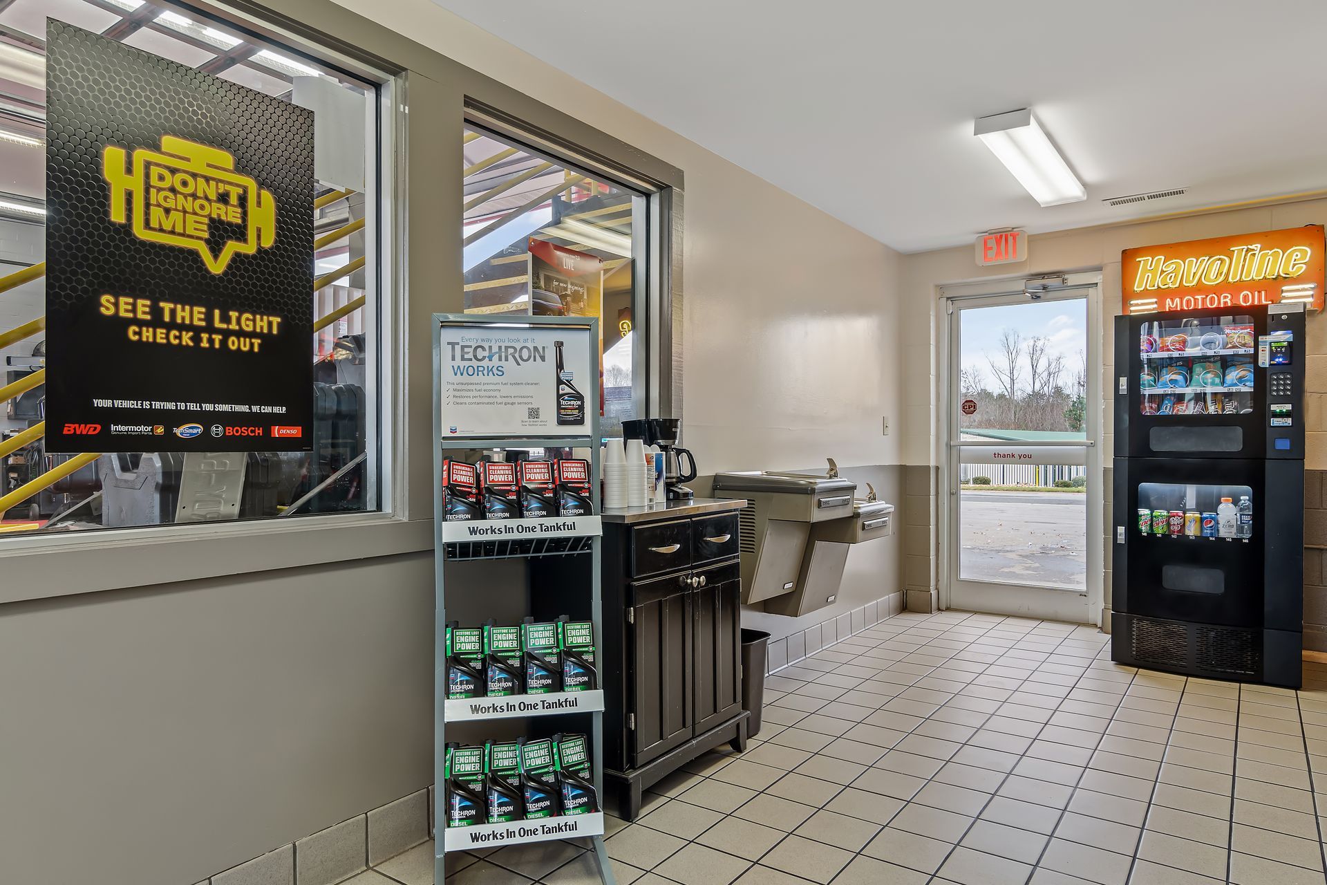 Interior of a convenience store with a drink cooler, snack shelves, and glass entrance doors.