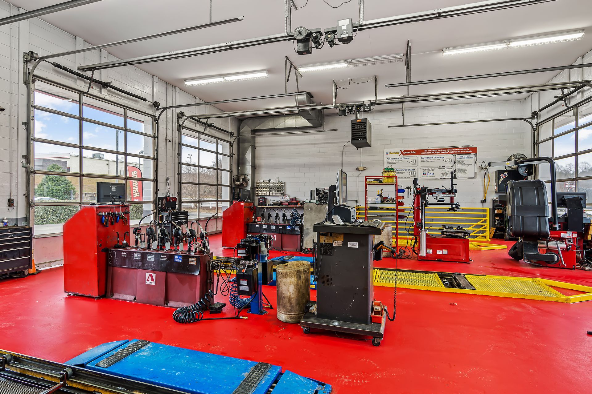Automotive repair shop with red floors, vehicle lifts, and maintenance equipment inside a garage