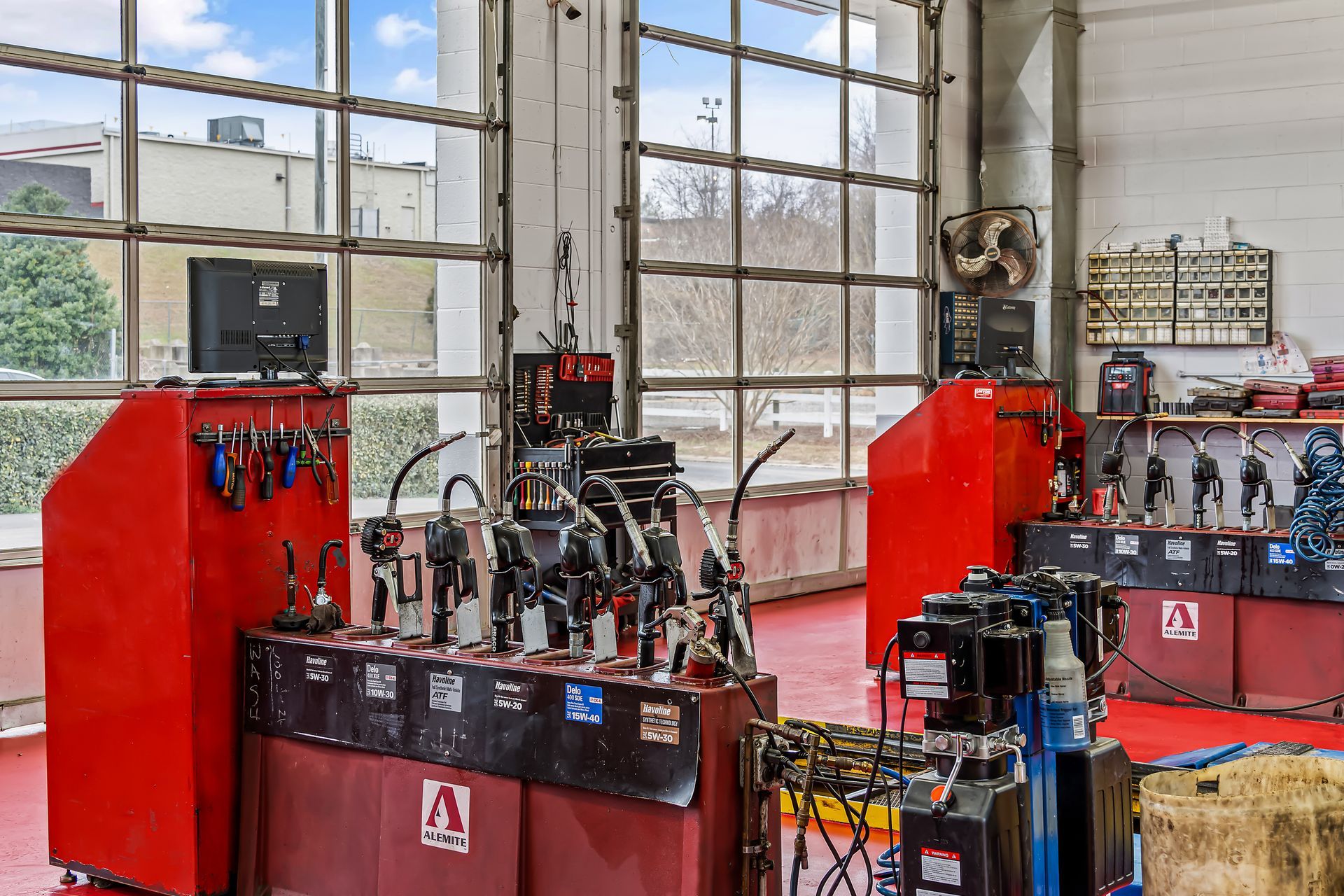 Red industrial workshop with machine parts on tables and large windows in the background