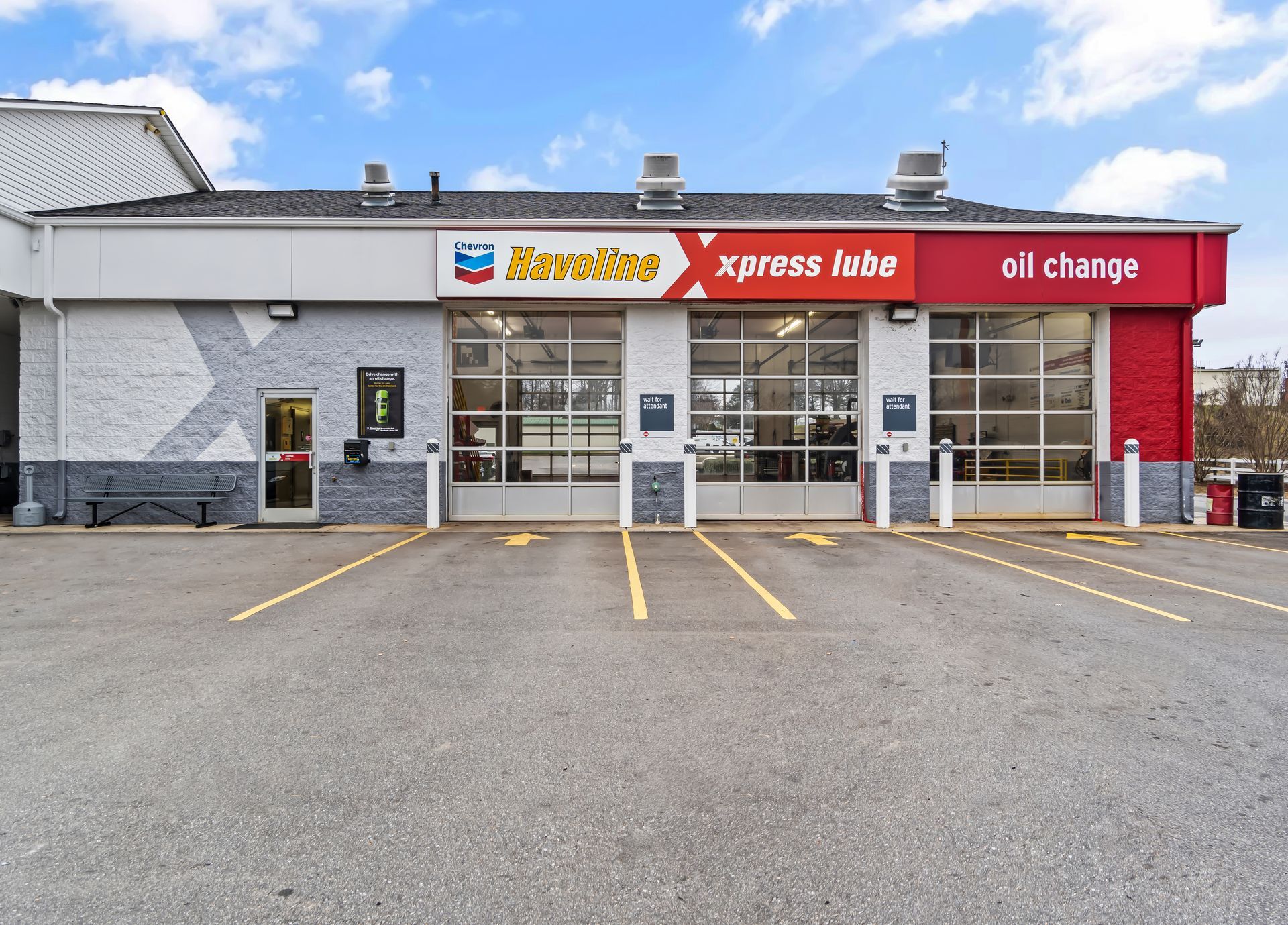 Storefront with yellow and red signage, glass doors, and empty parking spaces in front