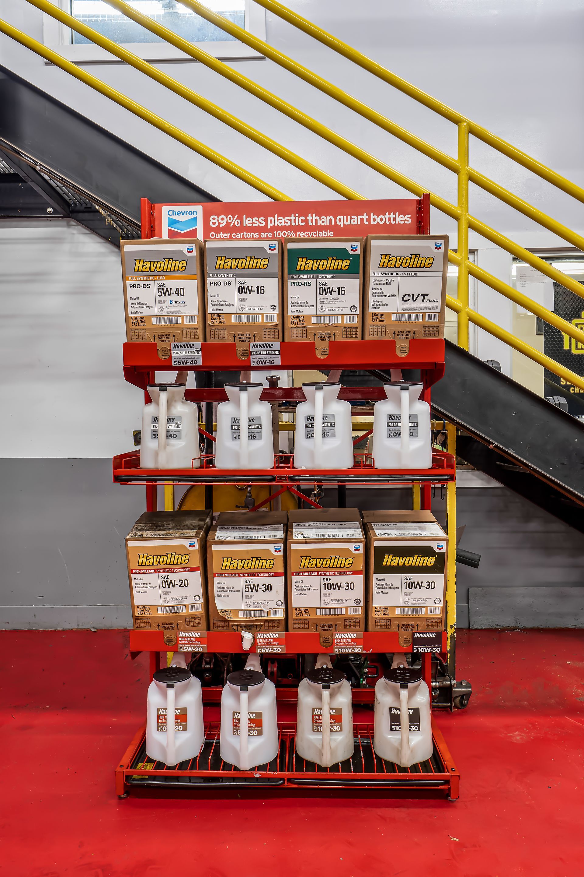Retail display of cleaning products on red shelving beside yellow stairs and a black escalator railing.